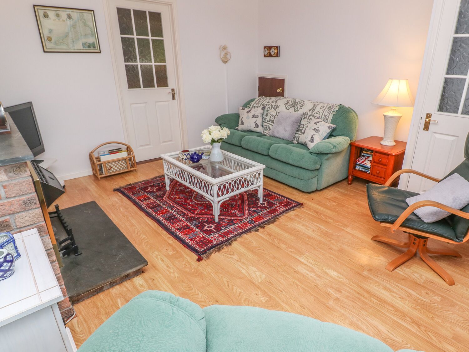 A cozy living room with a green sofa, a white coffee table, and a red patterned rug.