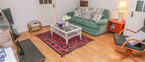 A cozy living room with a green sofa, a white coffee table, and a red patterned rug.