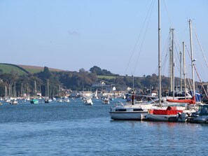 A marina with multiple sailboats docked, surrounded by hills and houses in the background. - Phenests (Falmouth)