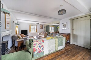 A cozy living room with a fireplace, a sofa, a dining area with a table, and a kitchen area.