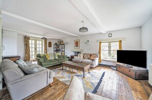 A living room with a sofa, armchairs, a coffee table, a television, and a patterned rug.