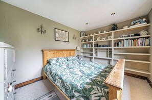 A bedroom with a wooden bed, a bookshelf, and a wardrobe. - Spring Park Farmhouse (Launceston)