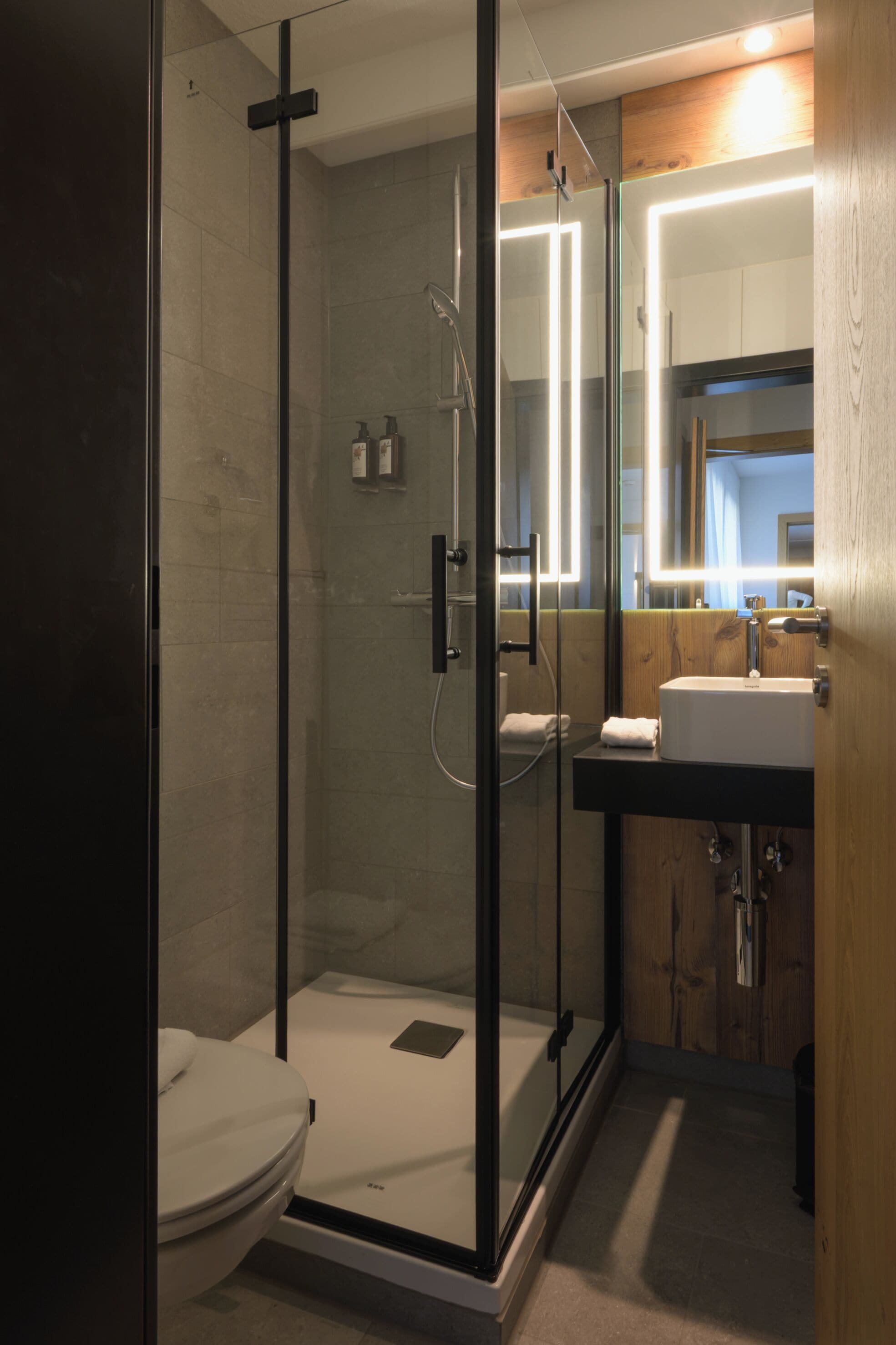 Een moderne badkamer met een douchecabine van glas, een toilet en een wastafel met spiegel.