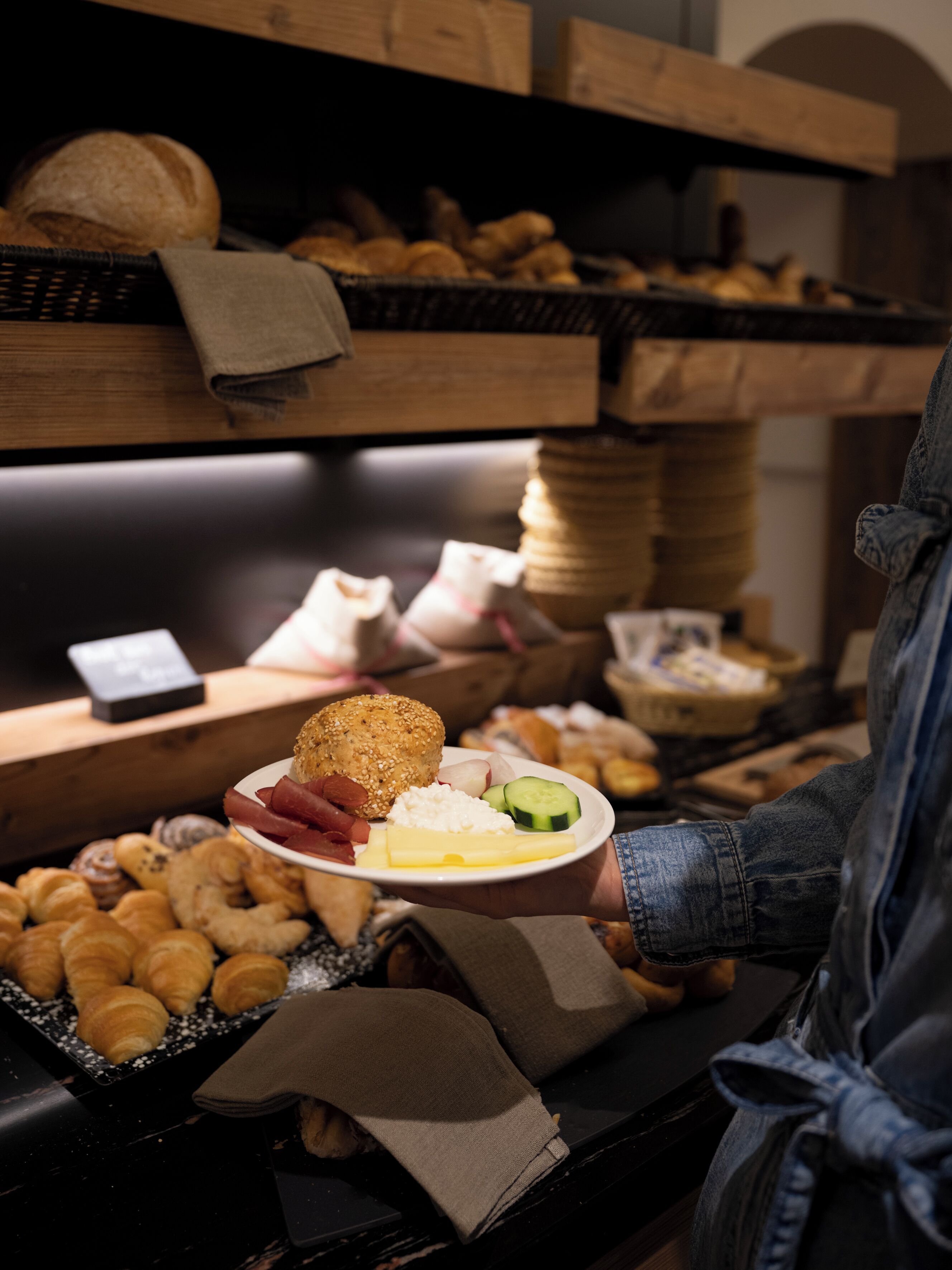 Ein Buffet mit verschiedenen Speisen, darunter Brot, Gebäck und eine Platte mit Käse, Radieschen und Fleisch.