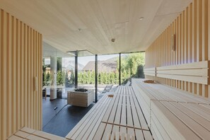 A modern interior with a wooden slatted wall, a bench, and a view of the outdoors. - Alpenhotel Montafon & SPA (Schruns)