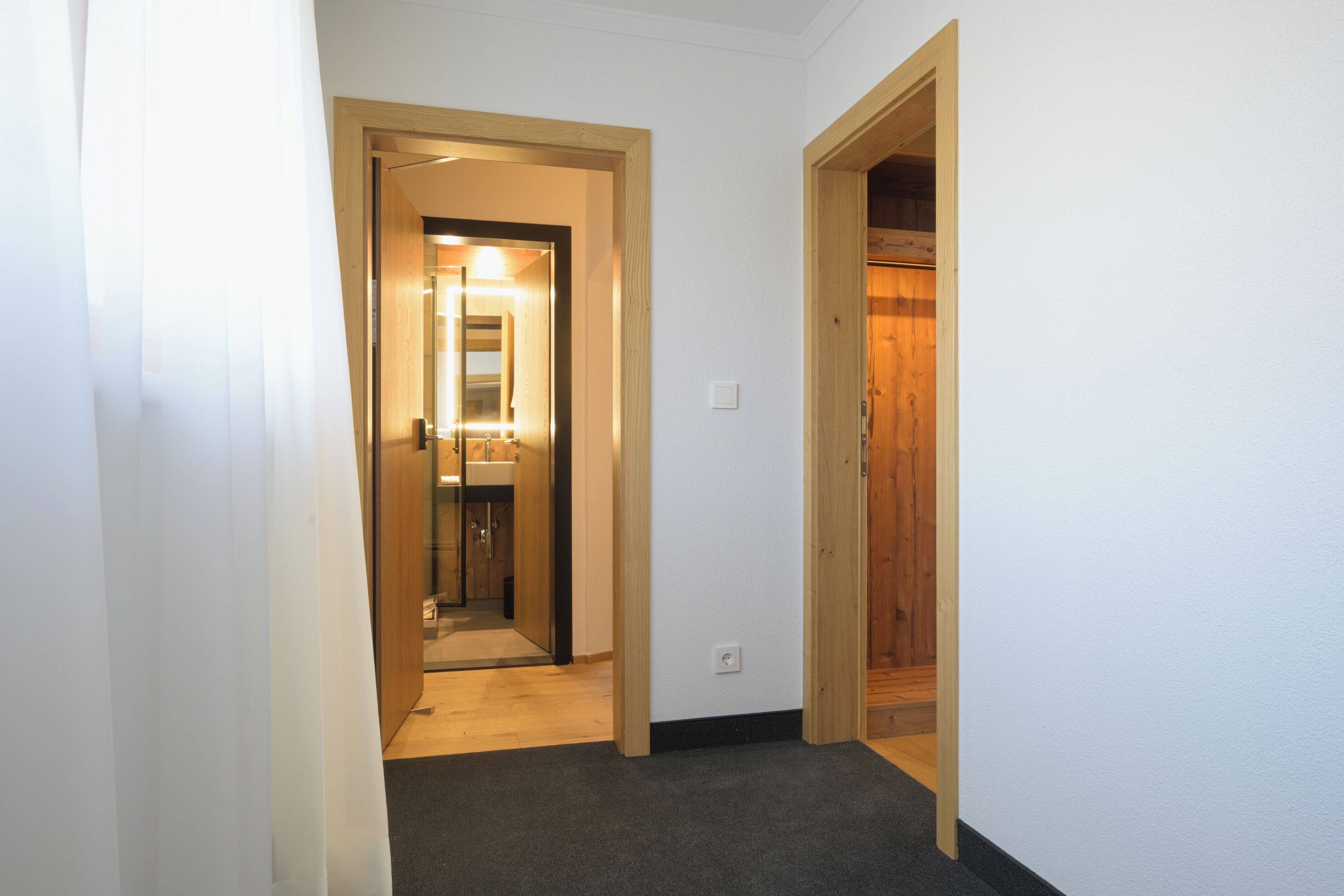 Un pasillo estrecho con una puerta de madera que da a un baño.
