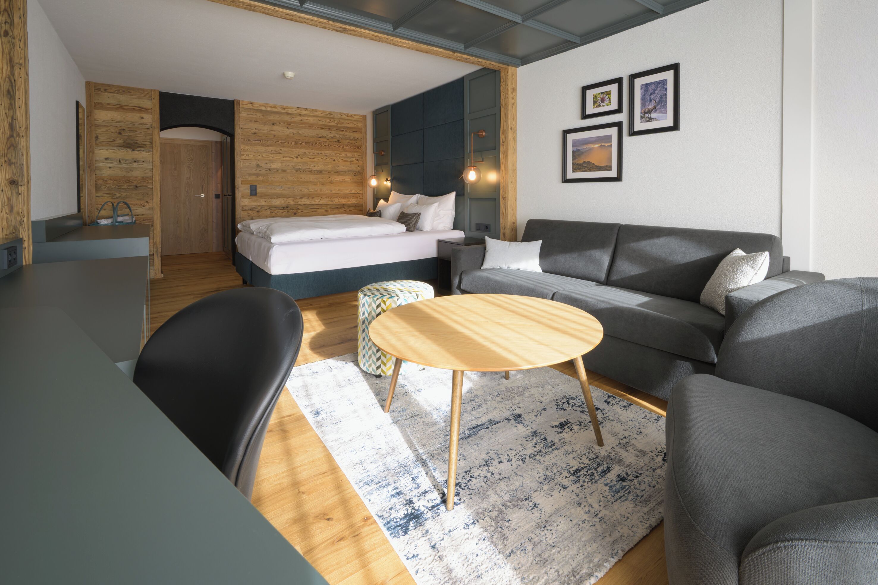 A modern hotel room with a bed, sofa, and a small round table.