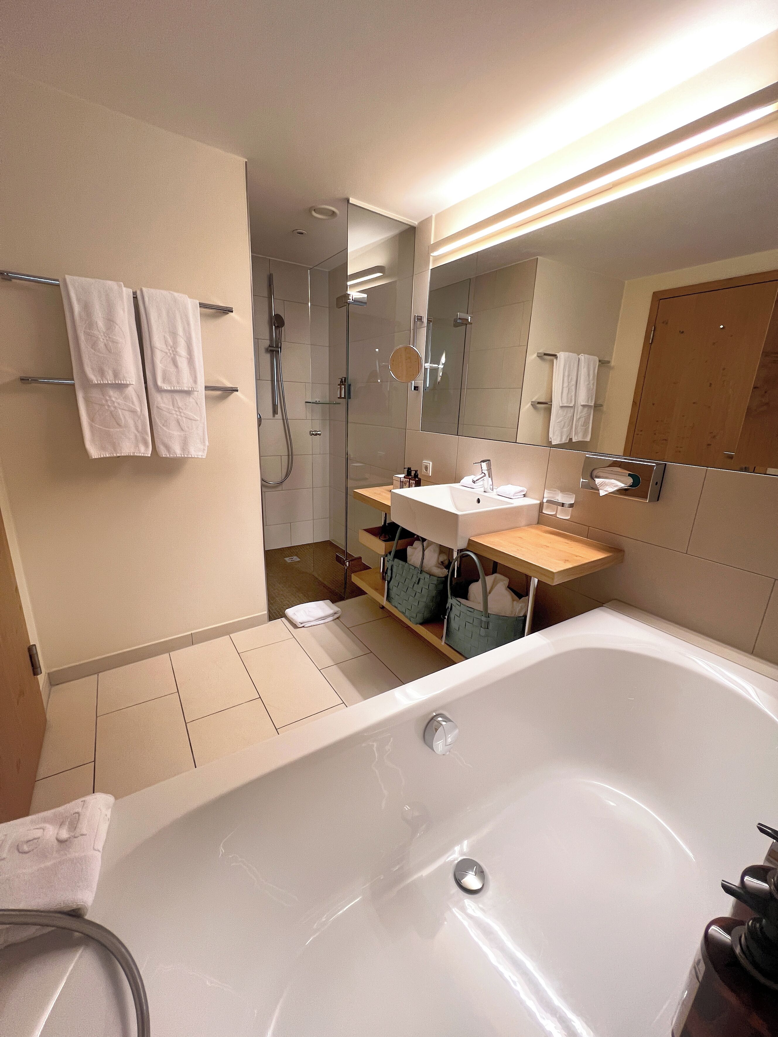 A modern bathroom with a bathtub, a glass-enclosed shower, and a vanity with a mirror.