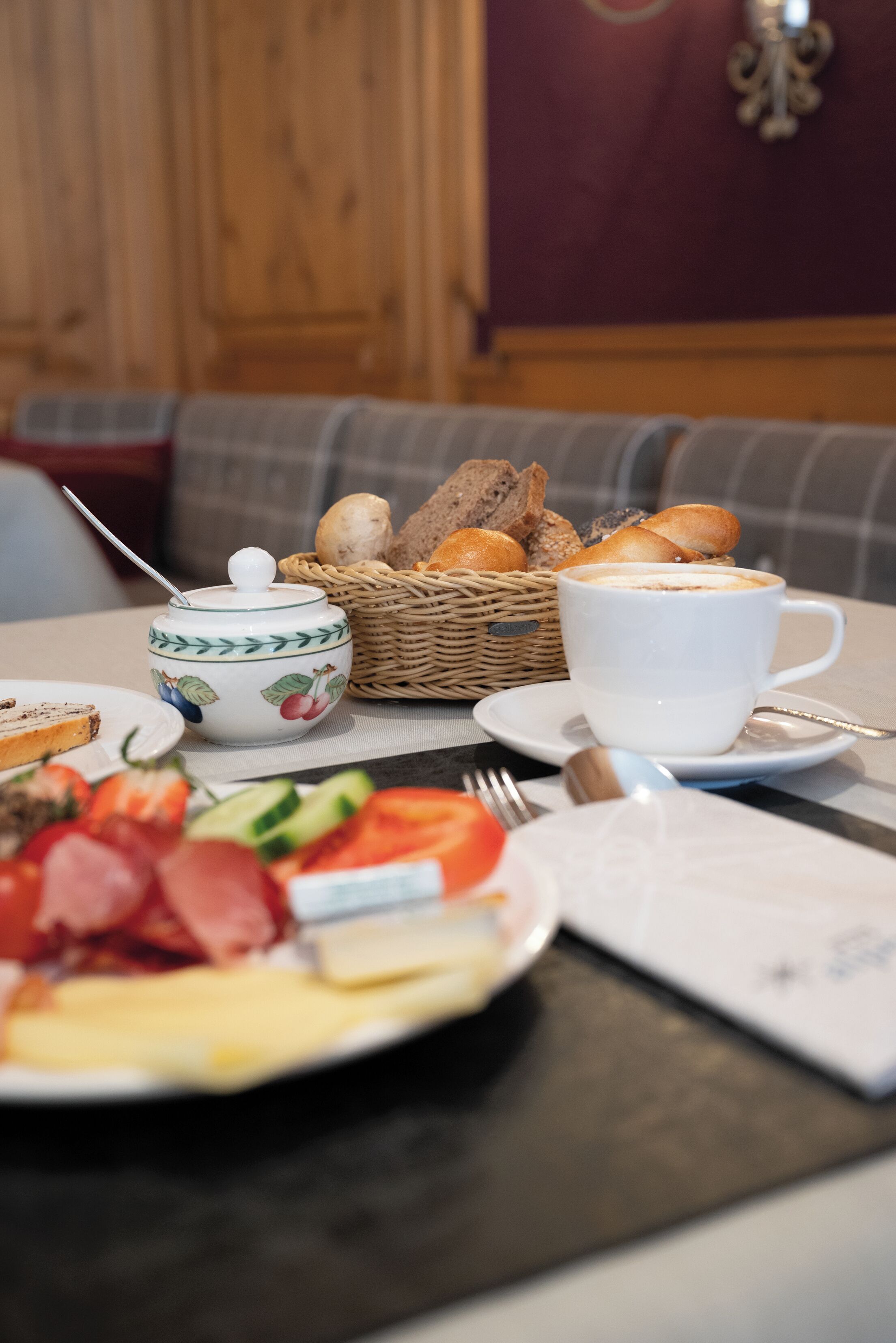 Ein Frühstückstisch mit einer Tasse Kaffee, einem Brotkorb und einem Teller mit Speisen.