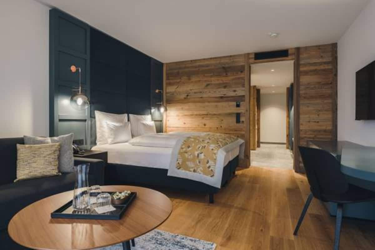 A modern hotel room with a bed, a desk, a chair, and a coffee table.