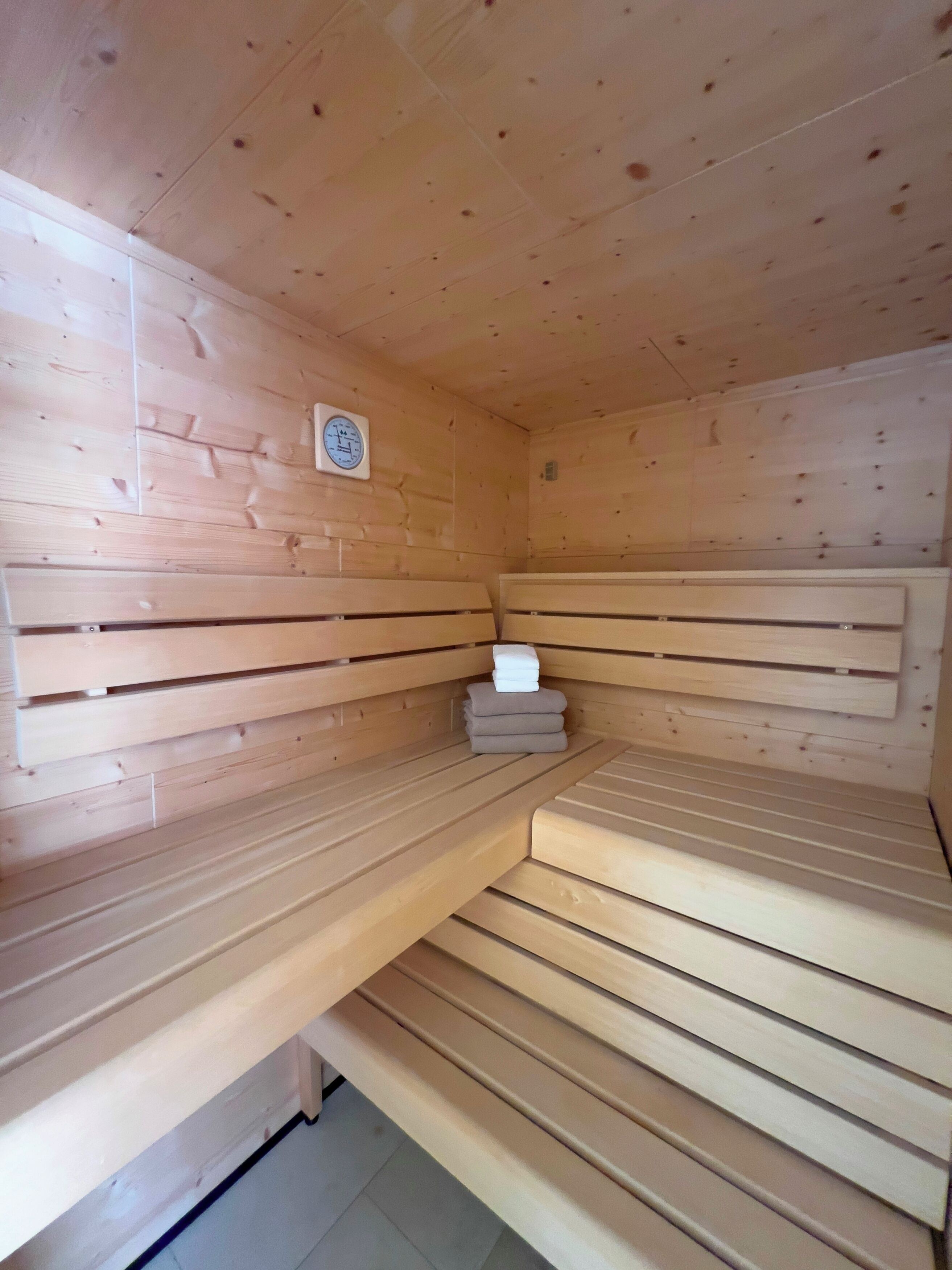A sauna with wooden benches and a control panel on the wall.