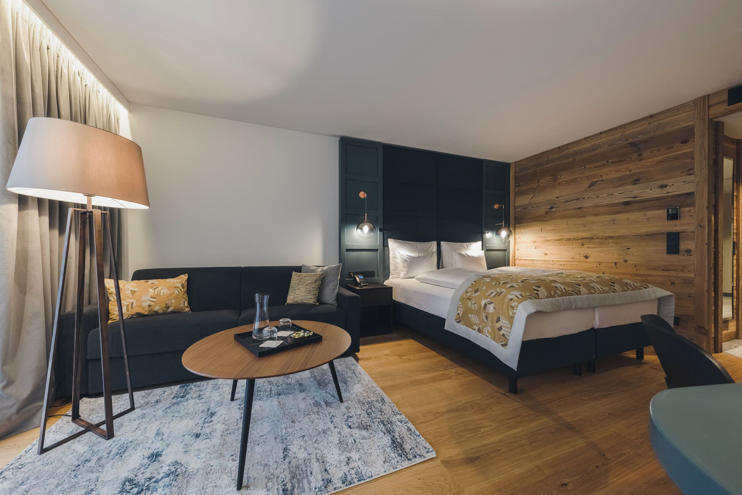 A modern bedroom with a bed, bedside tables, a sofa, a coffee table, and a lamp.