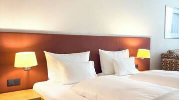 Ein Hotelzimmer mit einem großen Bett, zwei Nachttischlampen, einem Holznachttisch und einem gemusterten Sessel.