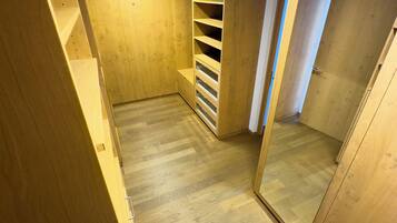 Un vestidor con estantes de madera y un espejo en la puerta.