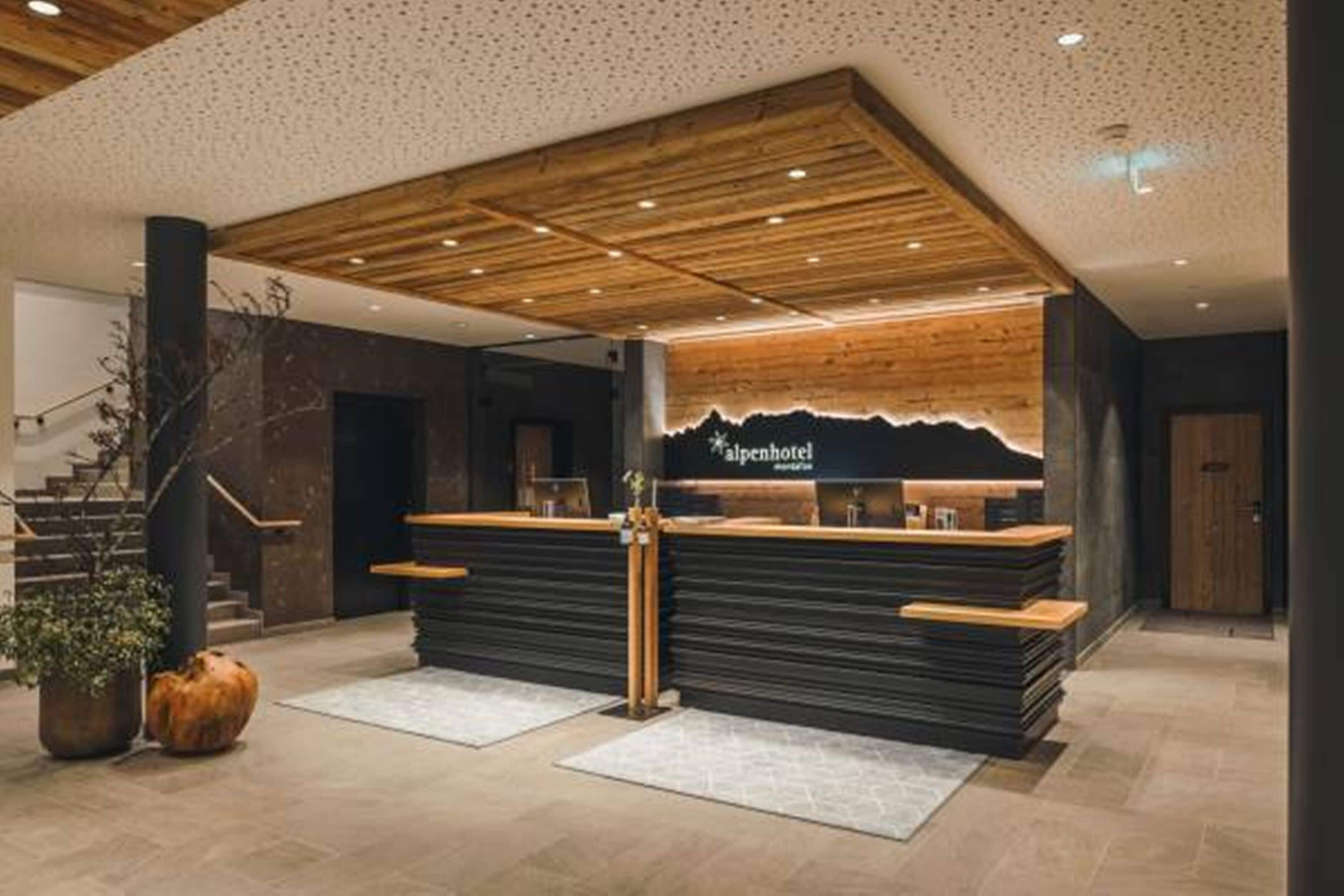 A reception area with a wooden ceiling, a reception desk, and a staircase to the left.