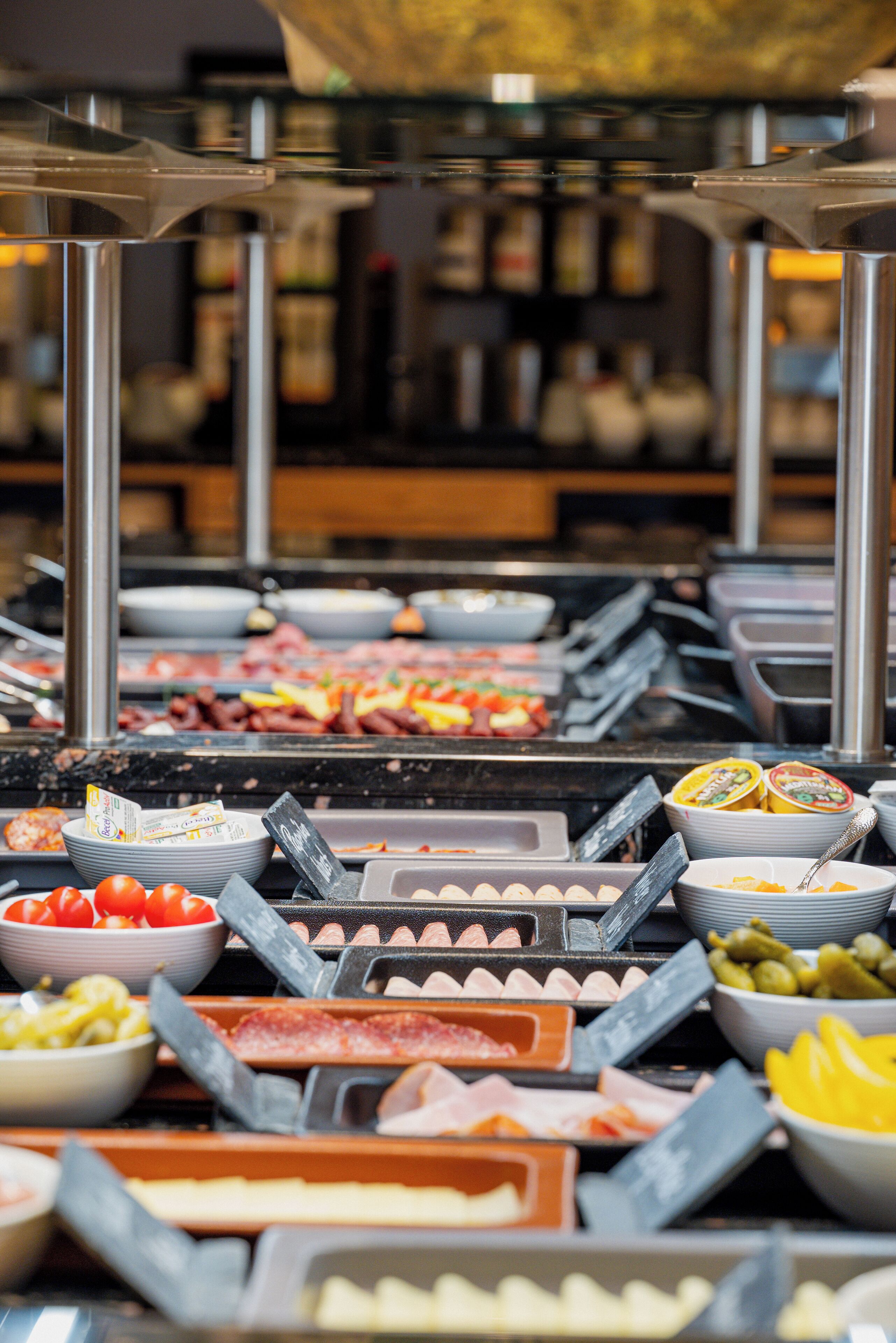 Un buffet proposant différents stands de nourriture, notamment des viandes, des fromages et des fruits.
