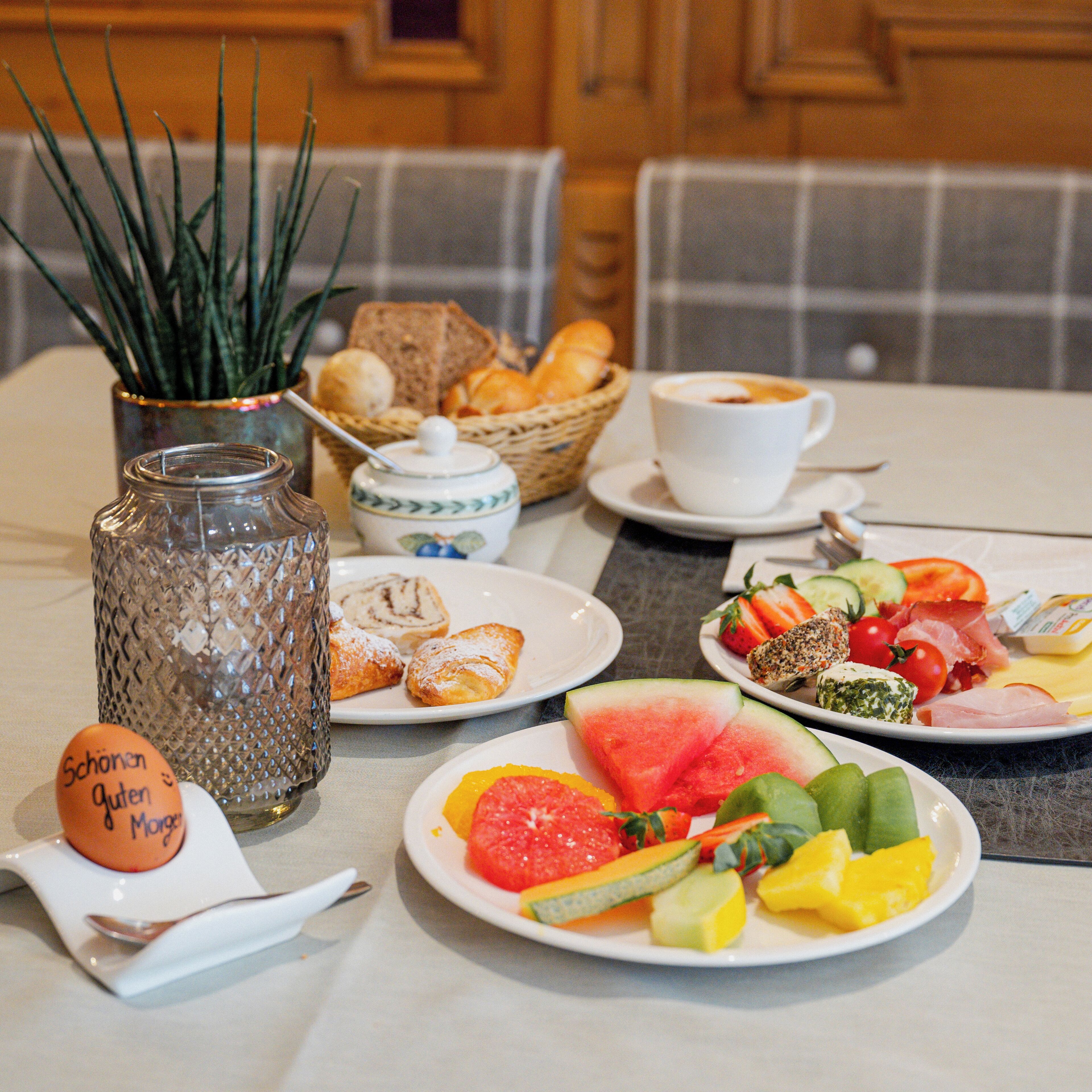 Une table de petit-déjeuner avec divers aliments, une tasse de café et un vase décoratif.