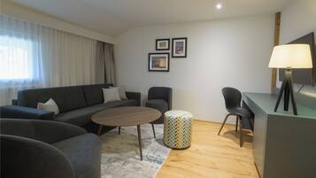 A modern living room with a sofa, chairs, a coffee table, and a lamp.