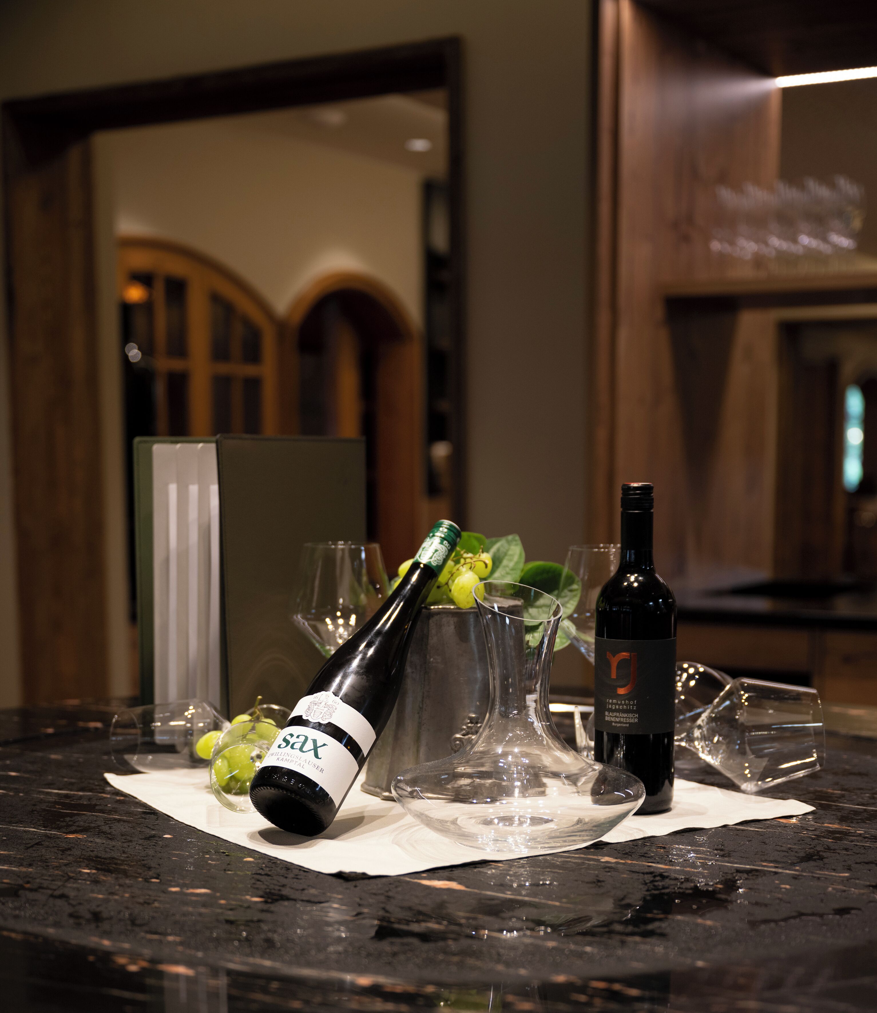 A bottle of wine and glasses on a marble countertop.