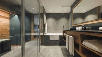 Un baño moderno con cabina de ducha de vidrio, una bañera independiente y un mueble de tocador de madera.