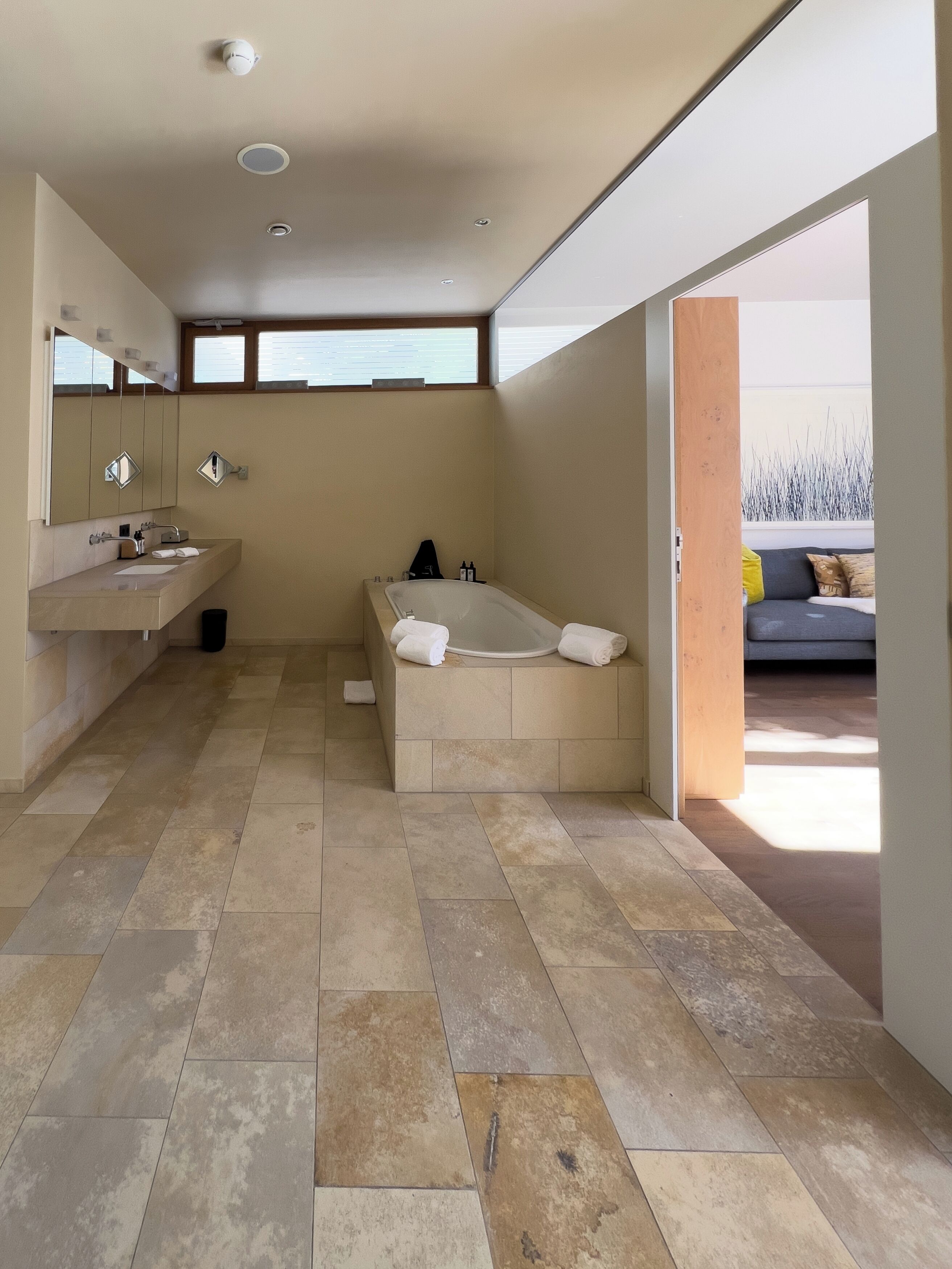 Un baño moderno con bañera, un espejo grande y tocador.