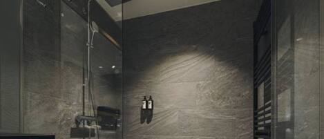 A modern shower area with a glass door, a handheld showerhead, and a built-in towel rack.