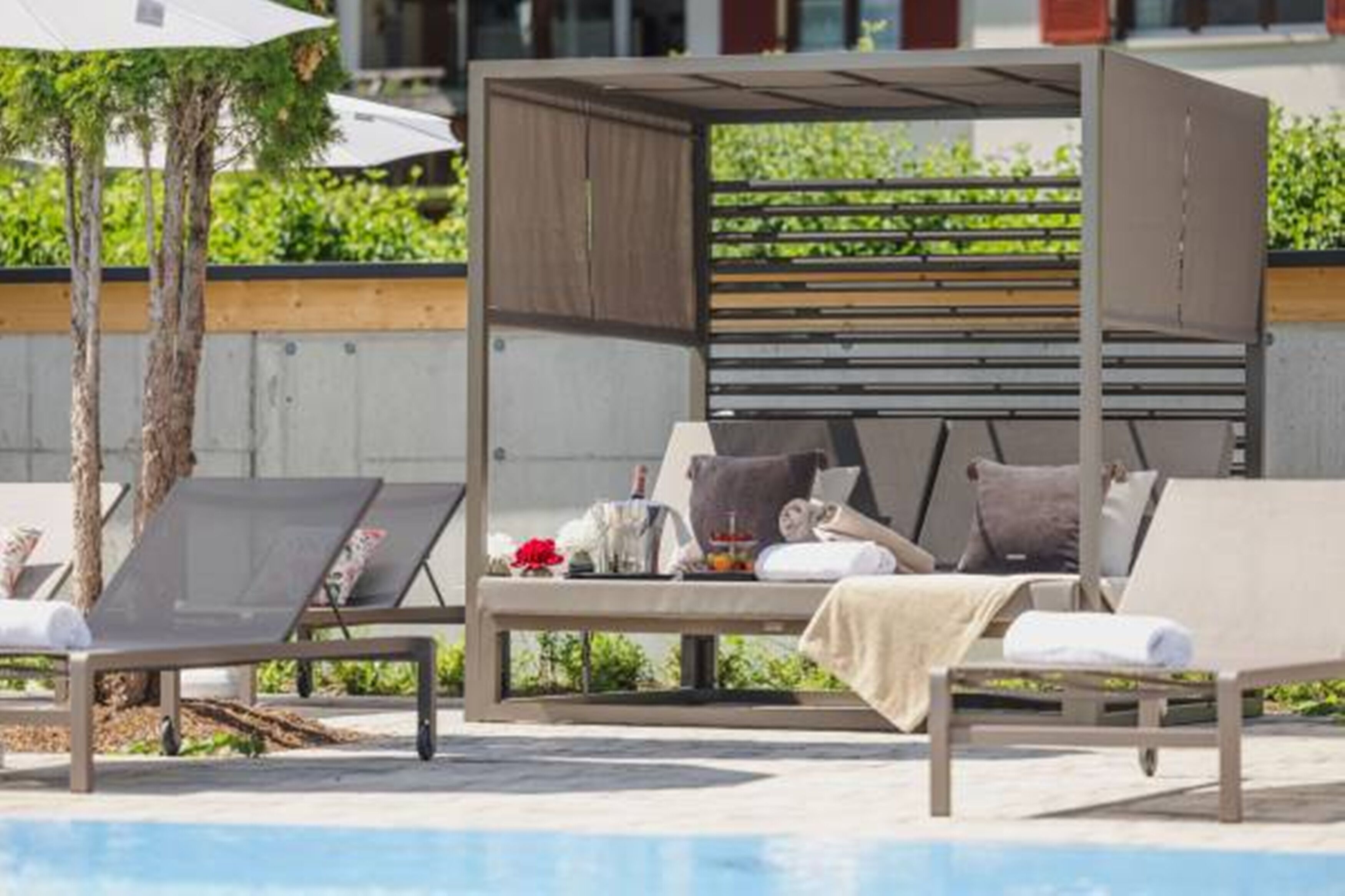 Ein Liegebereich am Pool mit Liegestühlen und einer überdachten Sitzgelegenheit.