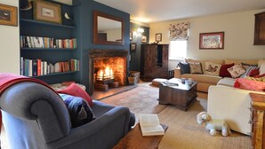 Un salon chaleureux avec une cheminée, une bibliothèque, un canapé et une table basse.