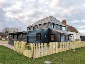 A two-story house with a dark wooden exterior and a light-colored wooden fence. - The Granary (Halstead)