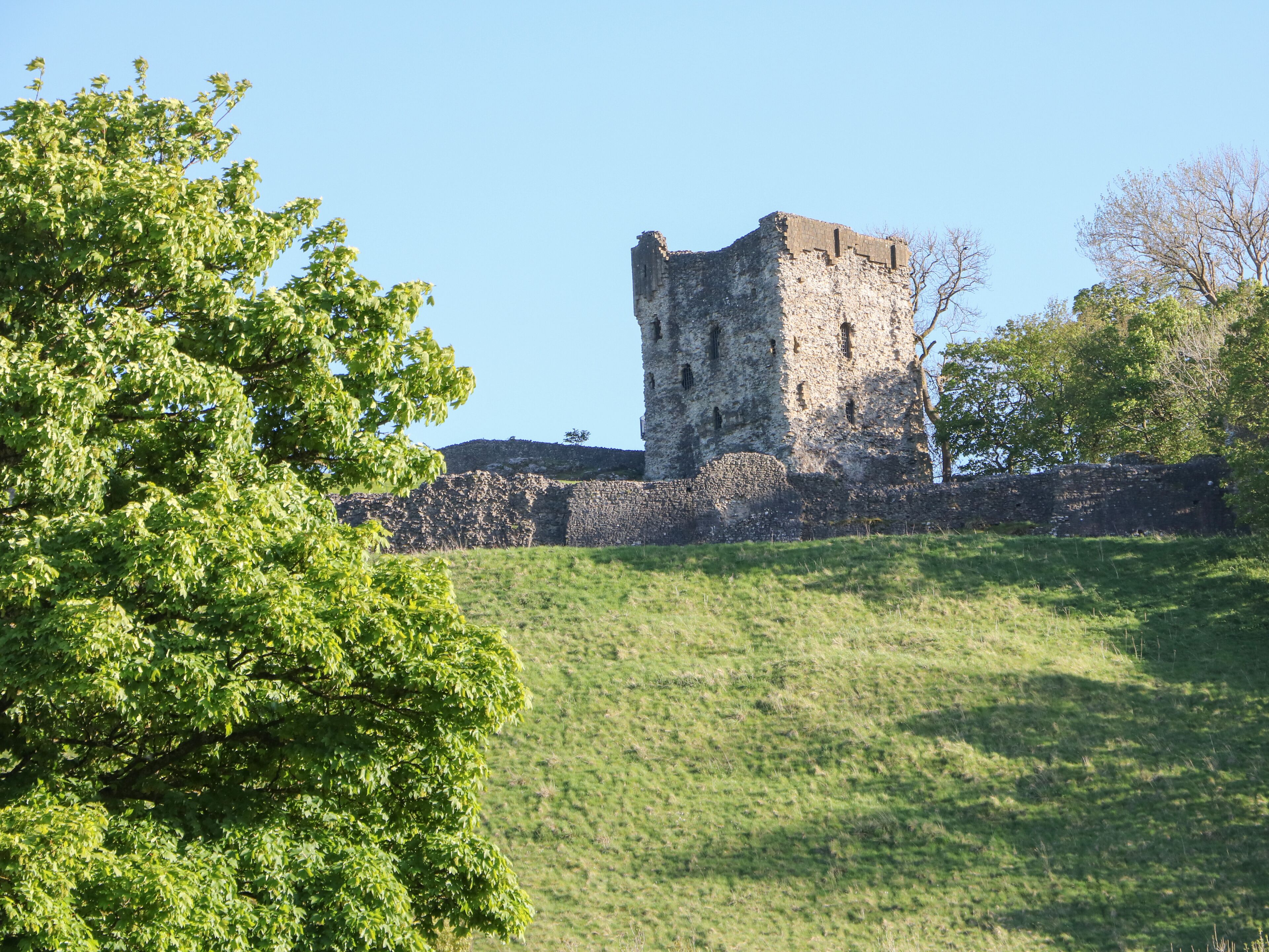 A historic stone tower with a grassy hill in the foreground.