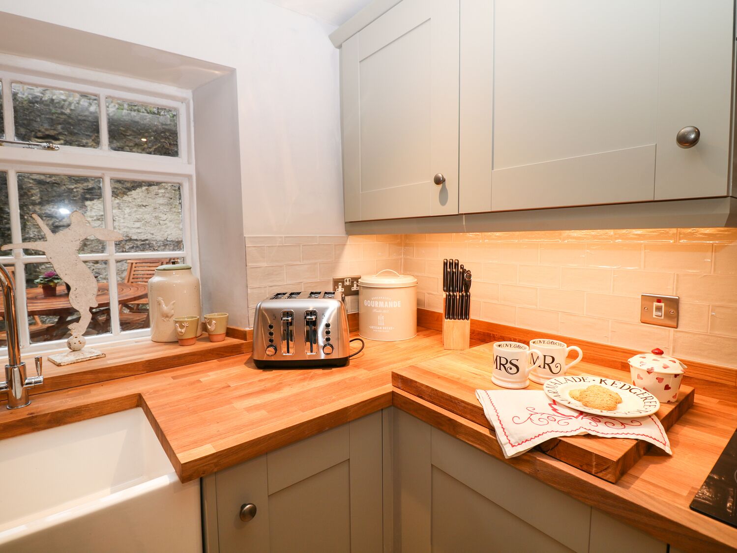 A kitchen with a toaster, a kettle, and mugs on the counter.