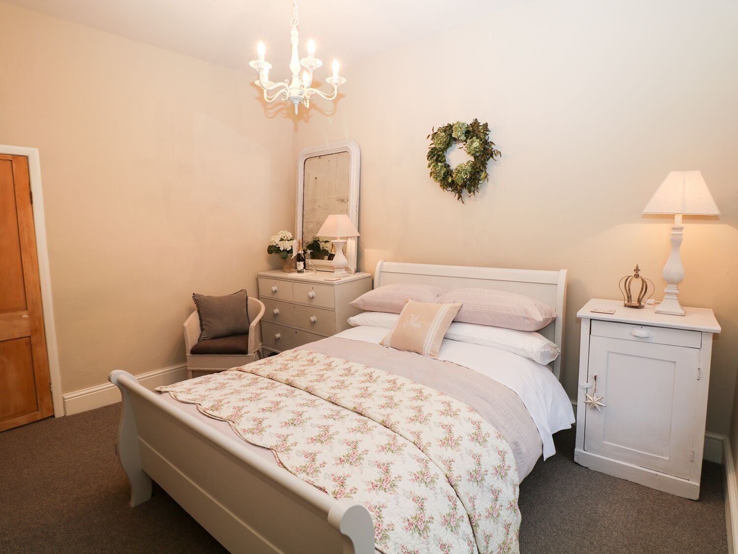 Een slaapkamer met een bed, een kaptafel, nachtkastje, stoel en een kroonluchter.