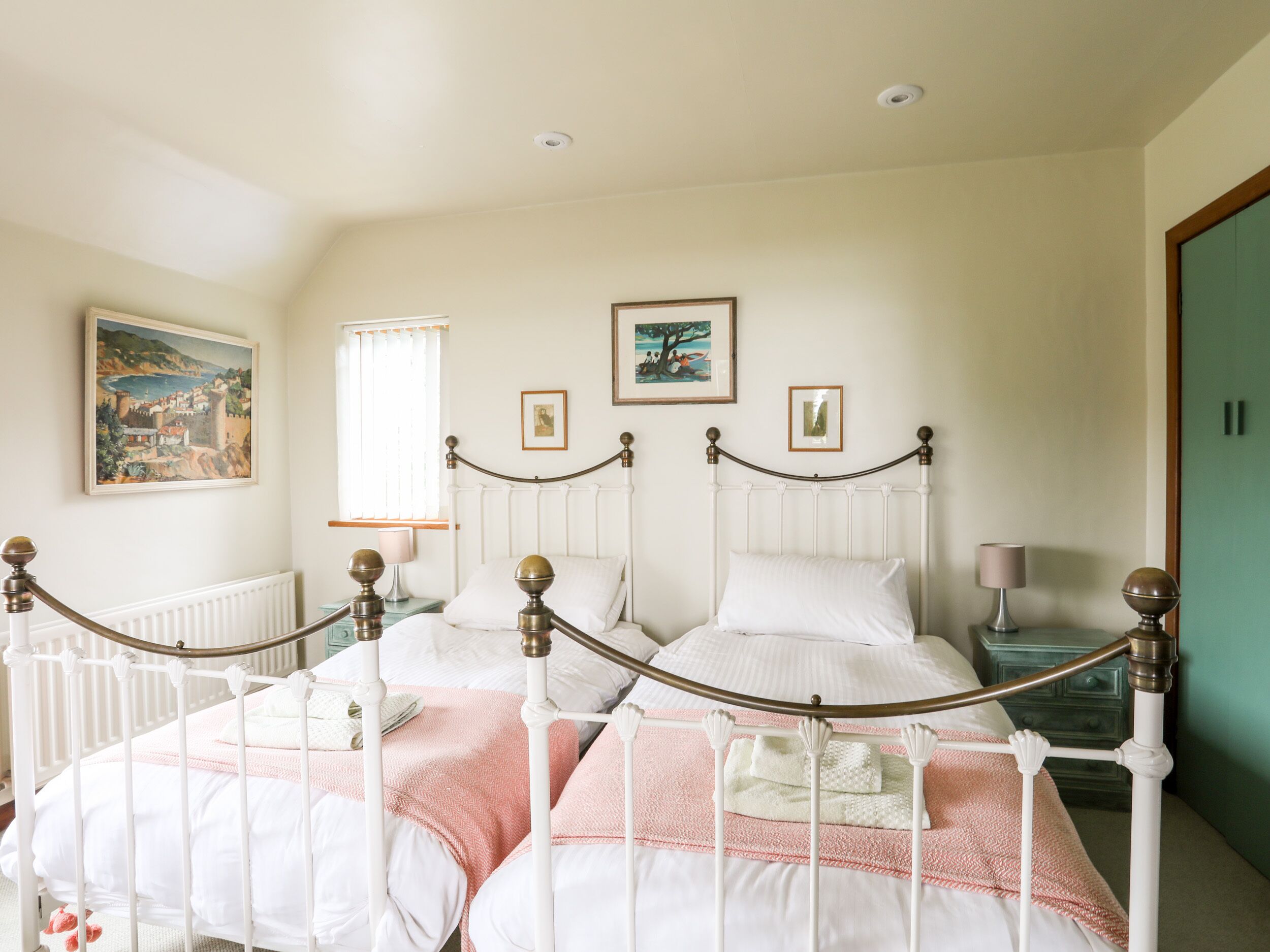A bedroom with a white four-poster bed, a window with blinds, and a green door.
