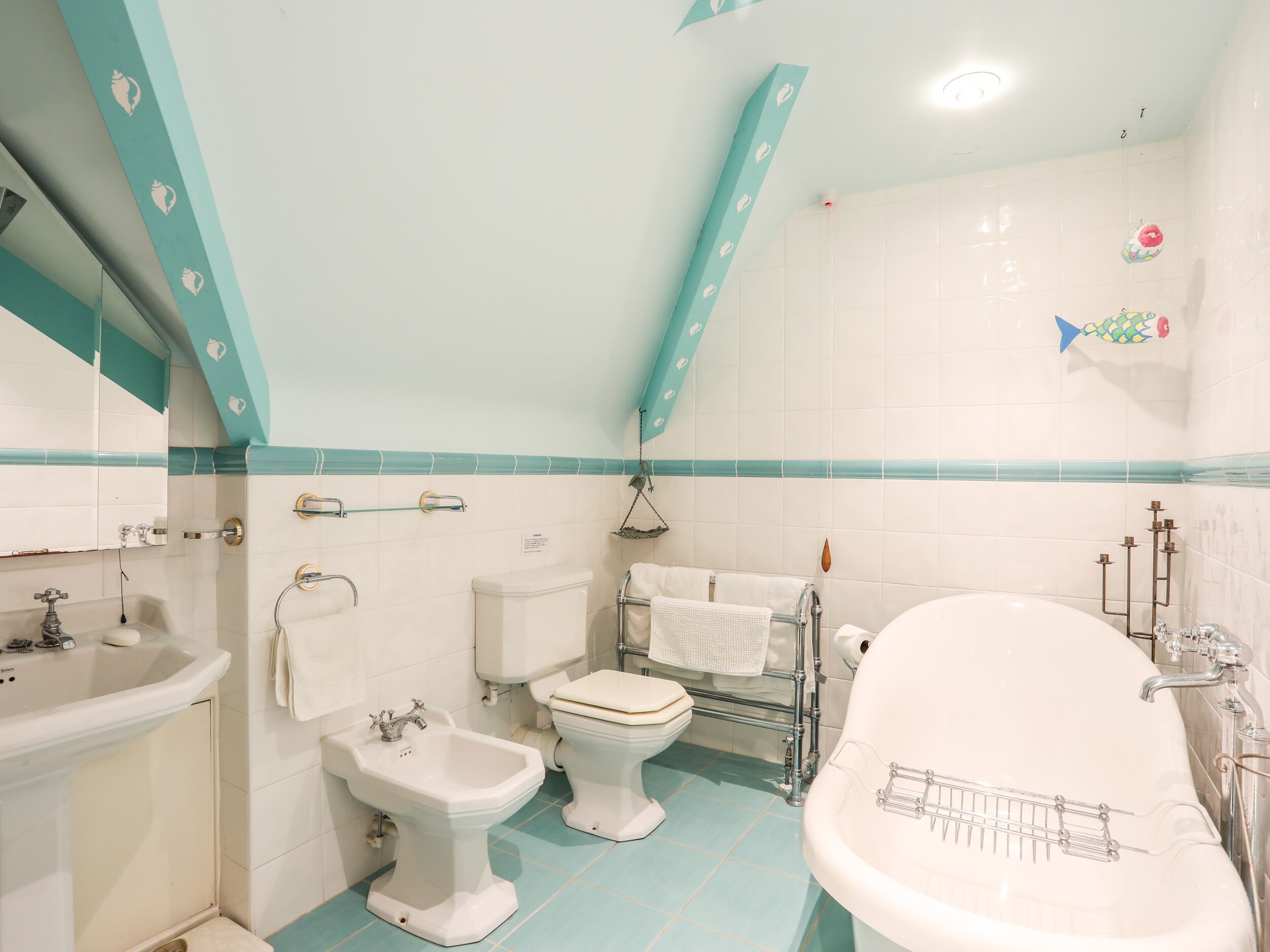 A bathroom with a sink, bidet, toilet, and bathtub.