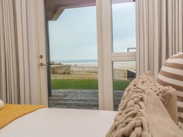 A bedroom with a large window overlooking a beach.