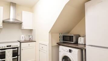 A compact kitchen with a built-in oven, microwave, and washing machine.
