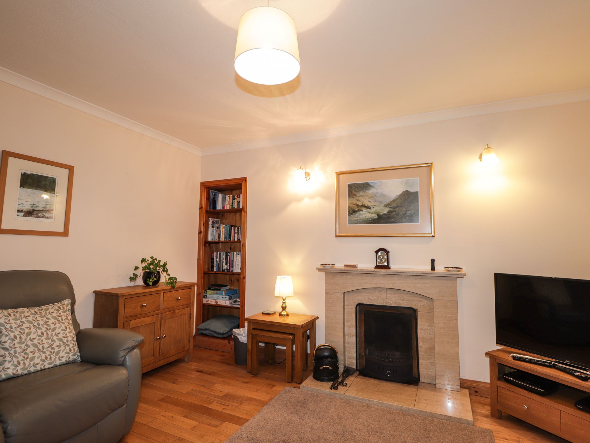 A living room with a sofa, a fireplace, a television, and a bookshelf.