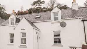 Una casa blanca con un letrero que dice "CRAIGARD" y un muro de piedra al frente.