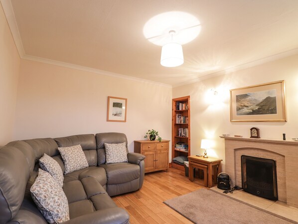 A living room with a sectional sofa, a fireplace, a bookshelf, and a framed picture on the wall. - Craigard (Kyle)