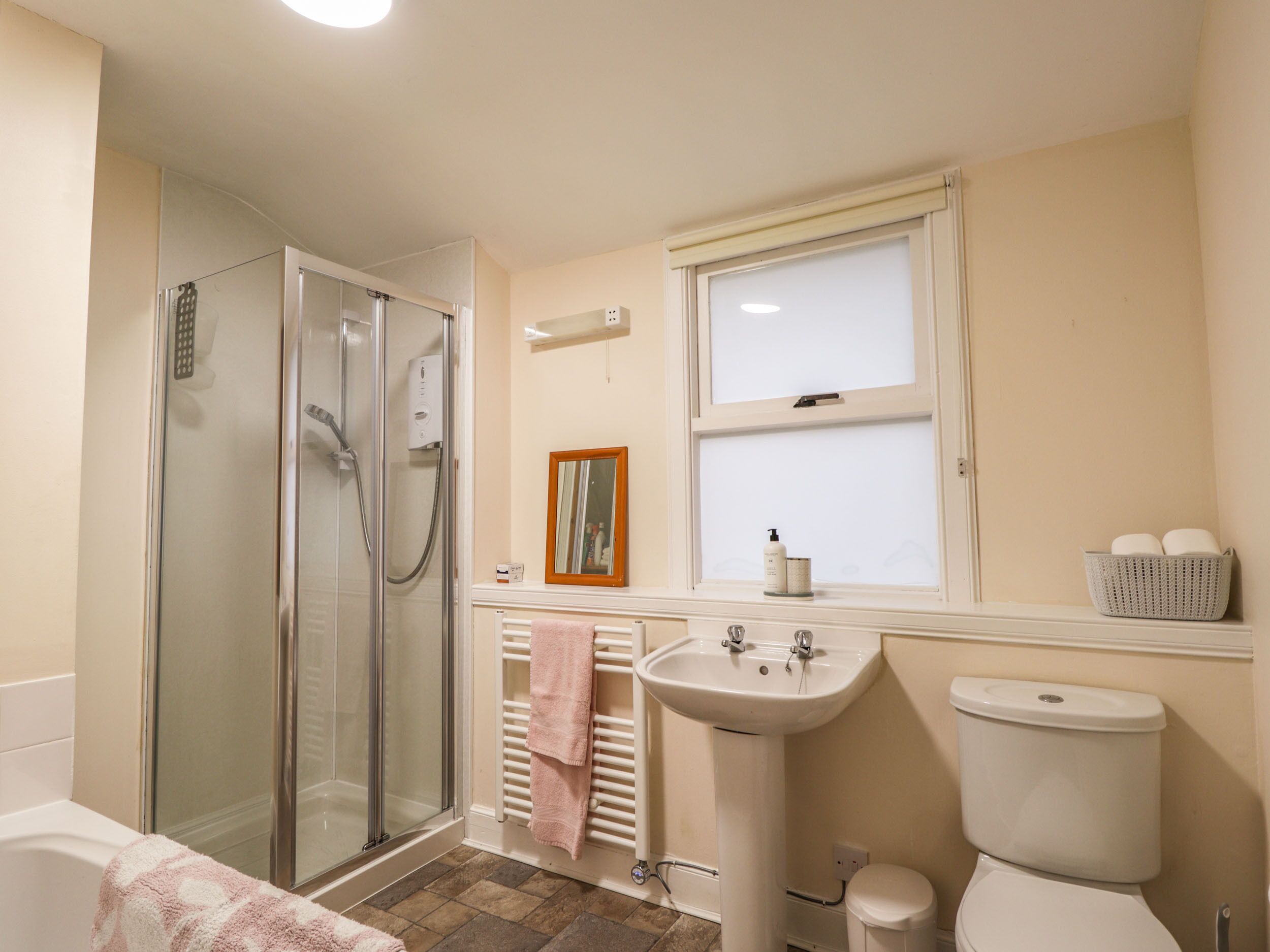 A bathroom with a glass-enclosed shower, a sink, a toilet, and a window.