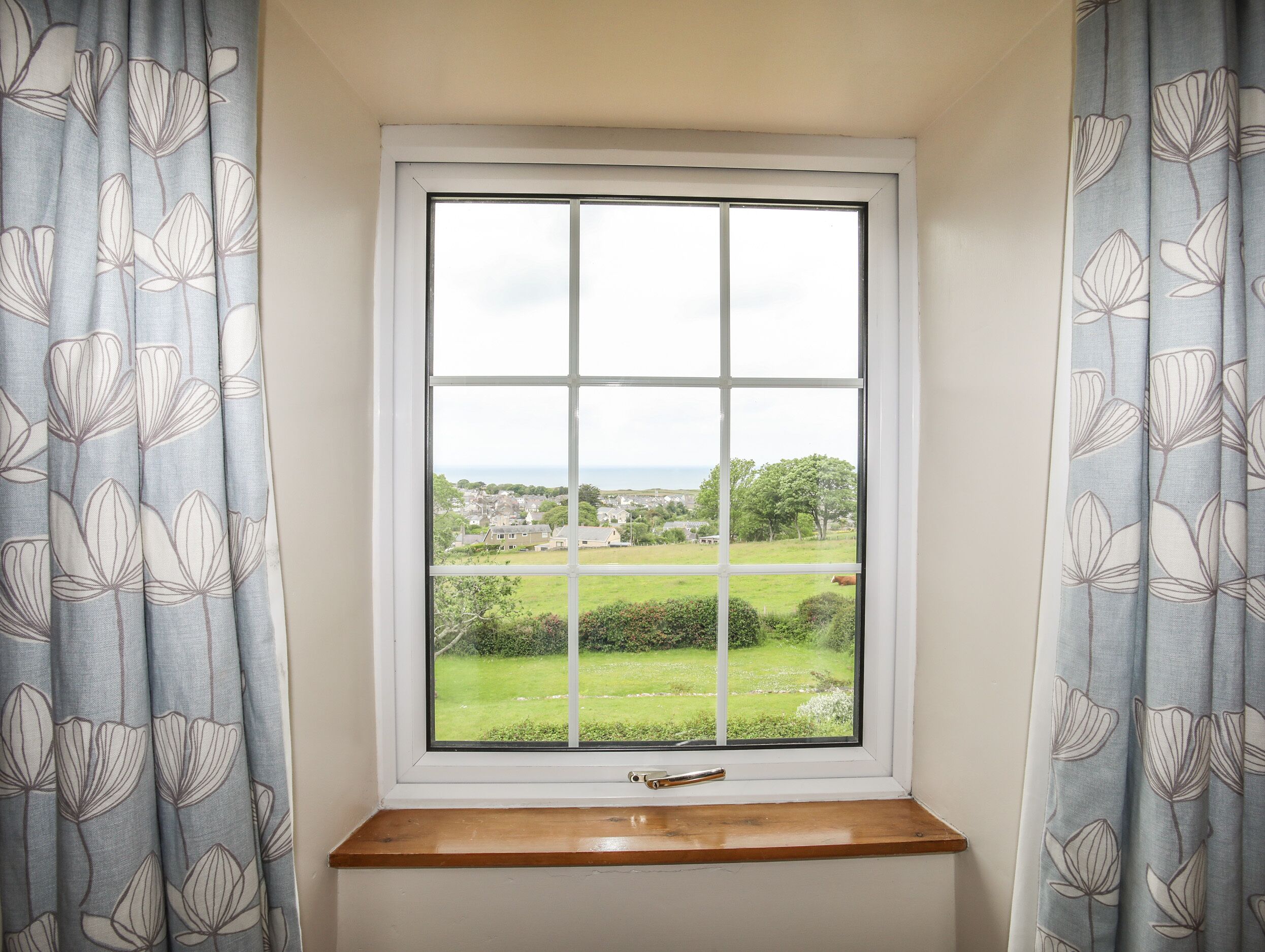 Ein Fenster mit Blick auf eine grüne Landschaft und eine Stadt in der Ferne.