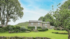 A stone house with a stone wall and a grassy lawn. - Fron Fawr (Pwllheli)