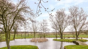 A serene park with a pond, surrounded by grassy areas and trees. - Wigrams Canalside Cottage (Southam)