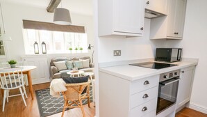 A compact kitchen with white cabinetry, a built-in microwave, and a stove. - 3 Poole End (Clitheroe)