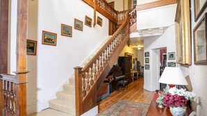 Una amplia escalera con balaustres de madera, piso alfombrado y una mesa con un jarrón de flores.