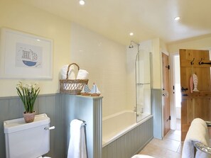 Bathroom features a toilet, shower, and bathtub, with a wicker basket and framed artwork.