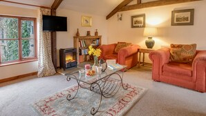 A cozy living room with a fireplace, two sofas, a coffee table, and a bookshelf.
