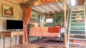 A rustic bedroom with a bed, a television, and a ladder. - Jackdaw's Roost (Gloucester)
