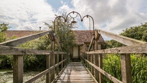 A wooden bridge leading to a stone building with a tiled roof. - Jackdaw's Roost (Gloucester)