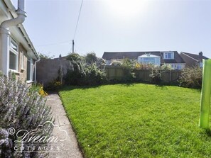A residential property with a well-maintained lawn, a pathway leading to the house, and a neighboring house visible in the background.